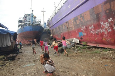Kids play between ships that were tossed on shore during storm surge nearly a year ago. Photo by Jude Bautista